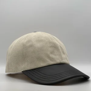 Berluti linen cap, three-quarter view showing the black leather brim and tonal top button.