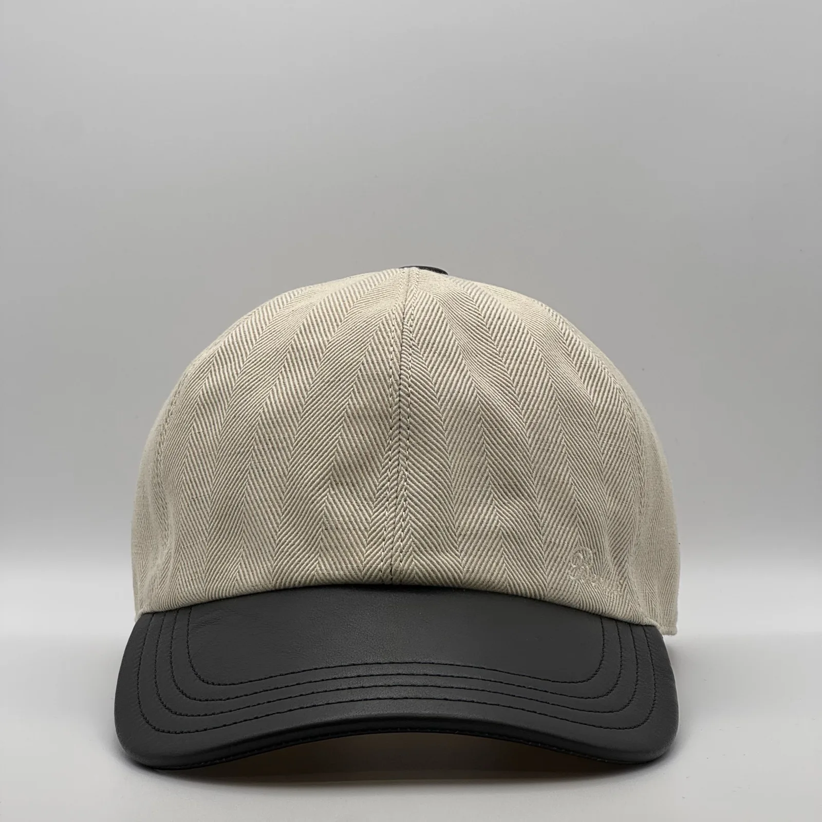 Berluti linen cap, front view in cream herringbone linen with a black leather brim.