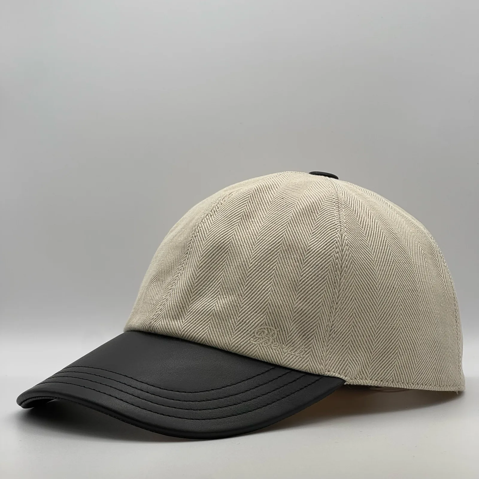 Berluti linen cap, side profile in herringbone linen with a black leather brim.