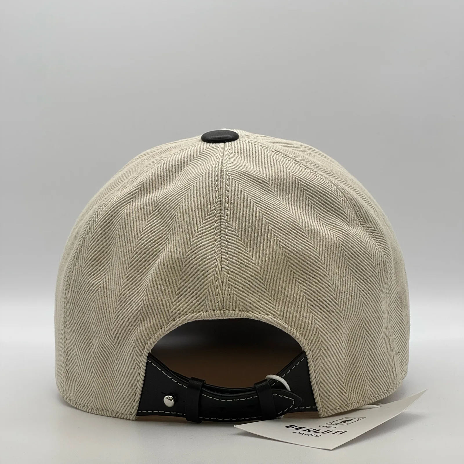Berluti linen cap, back view showing the curved black leather strap and buckle closure.