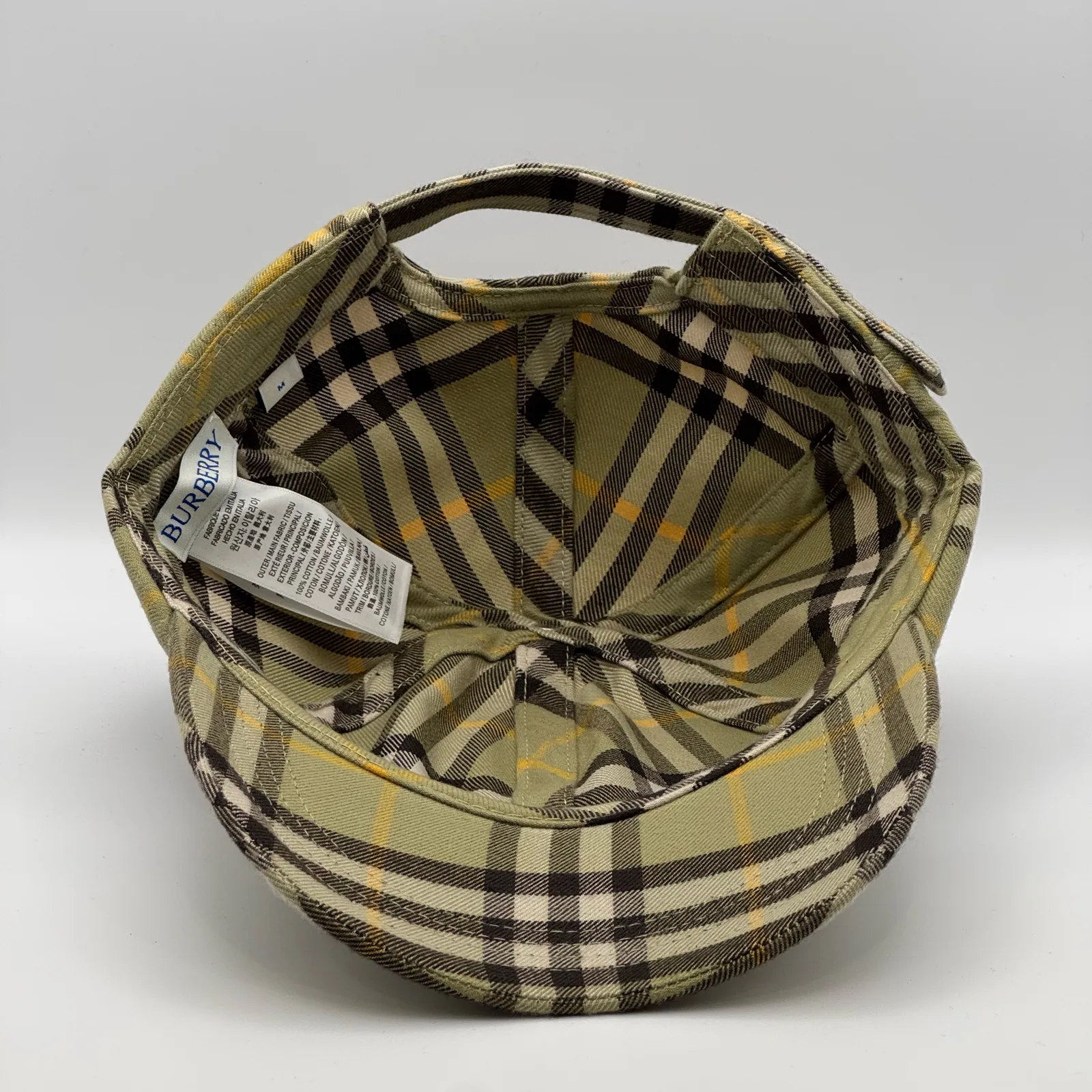 Underside of the olive check cap, brim lifted to show the interior and tags.
