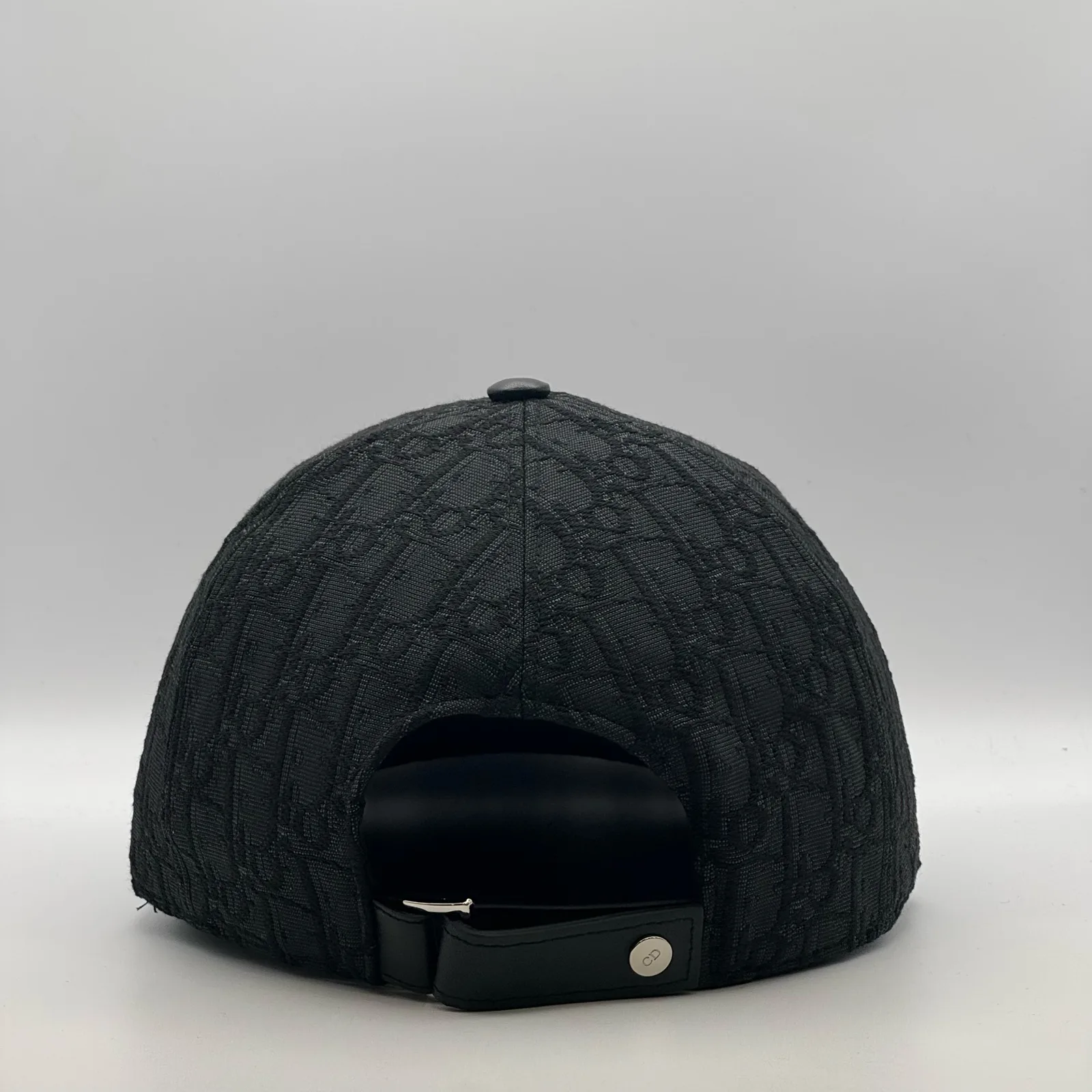Black Dior Oblique cap, back view showing the leather strap closure.