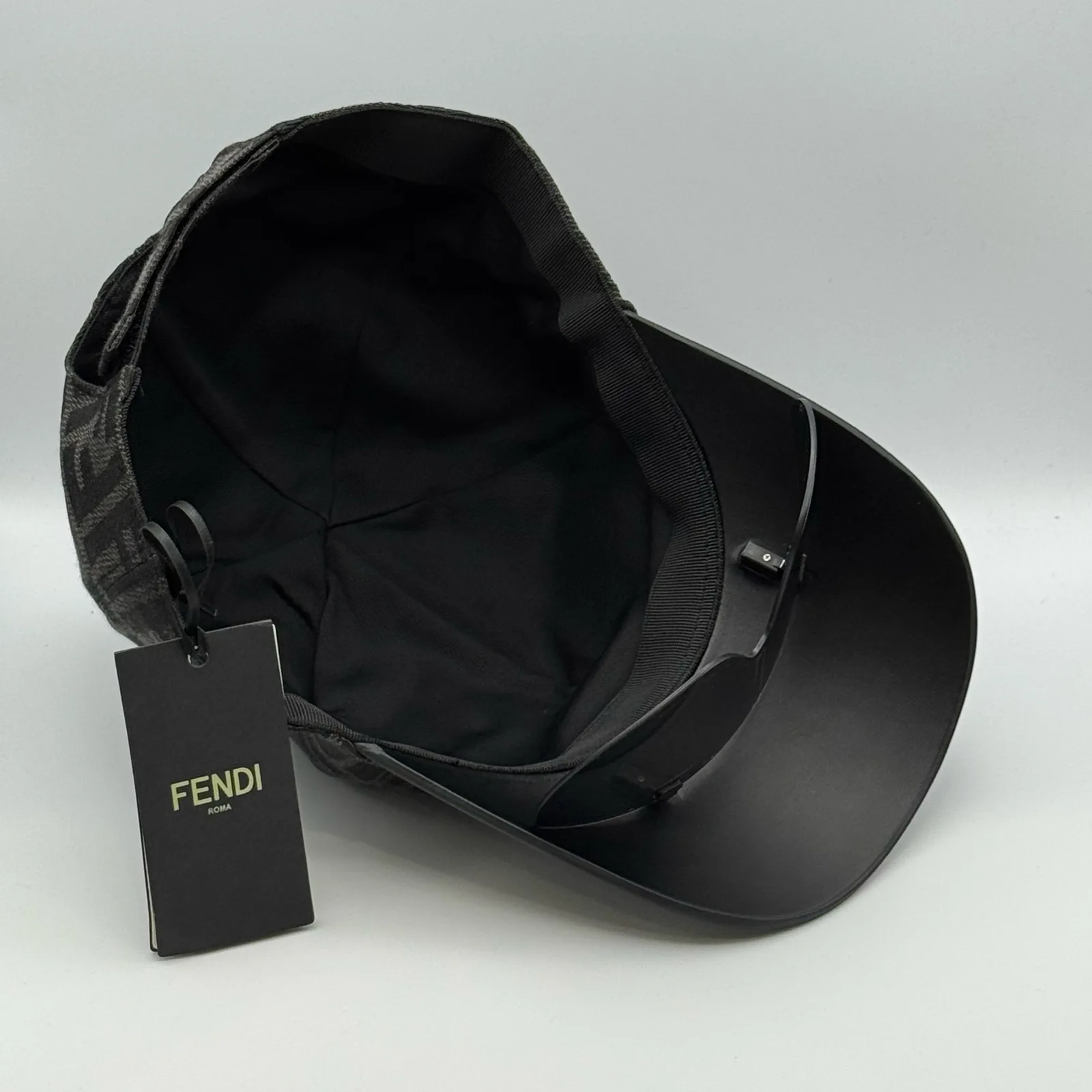 Underside of the black Fendi Visor cap with the Fendi hangtag attached at the brim.