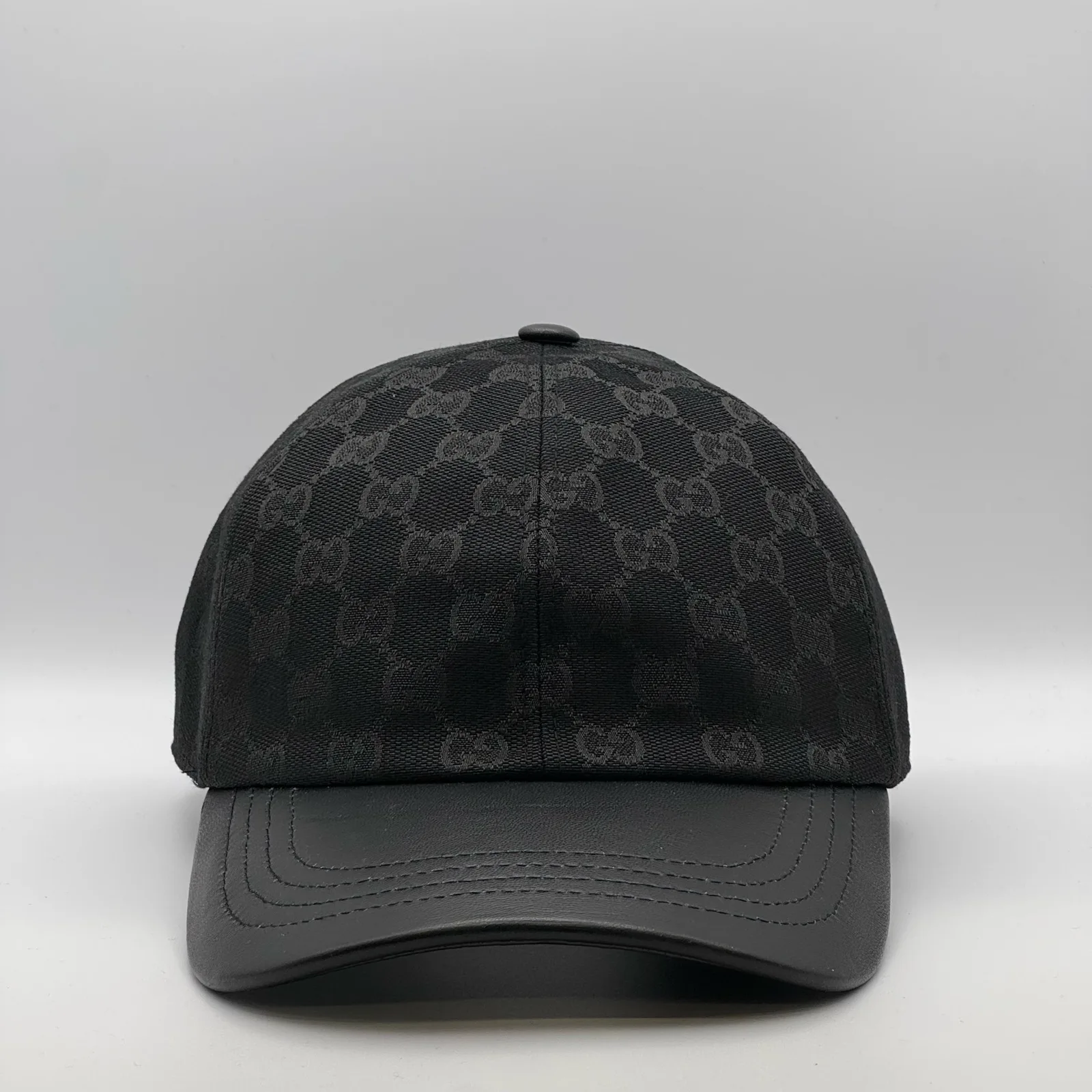Black GG canvas cap, front three-quarter view with a smooth black leather brim