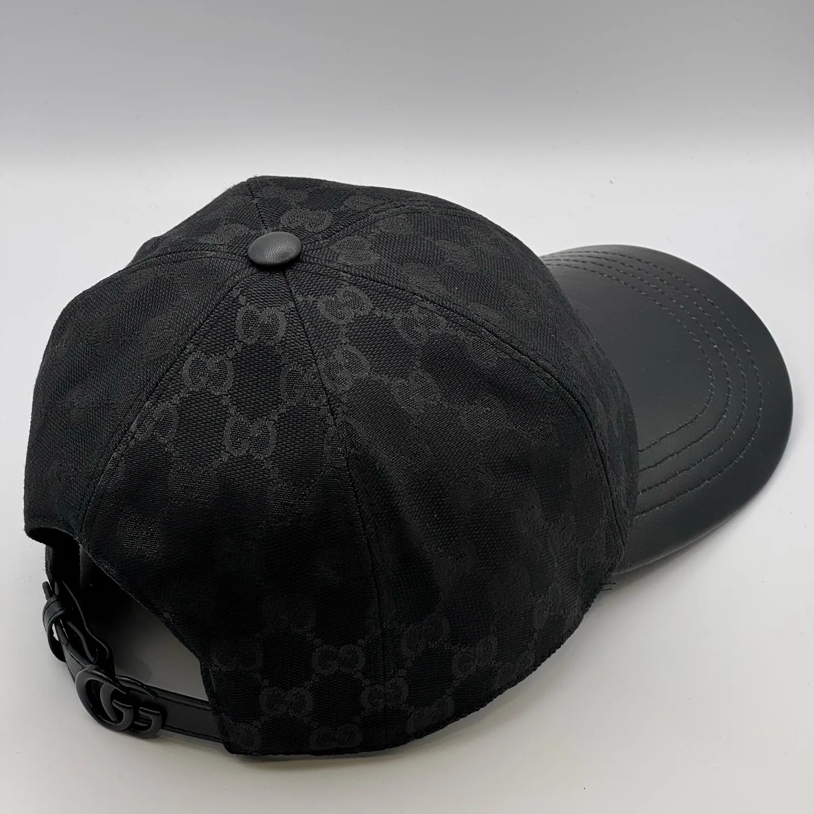Black GG canvas cap, three-quarter view showing the crown and leather brim