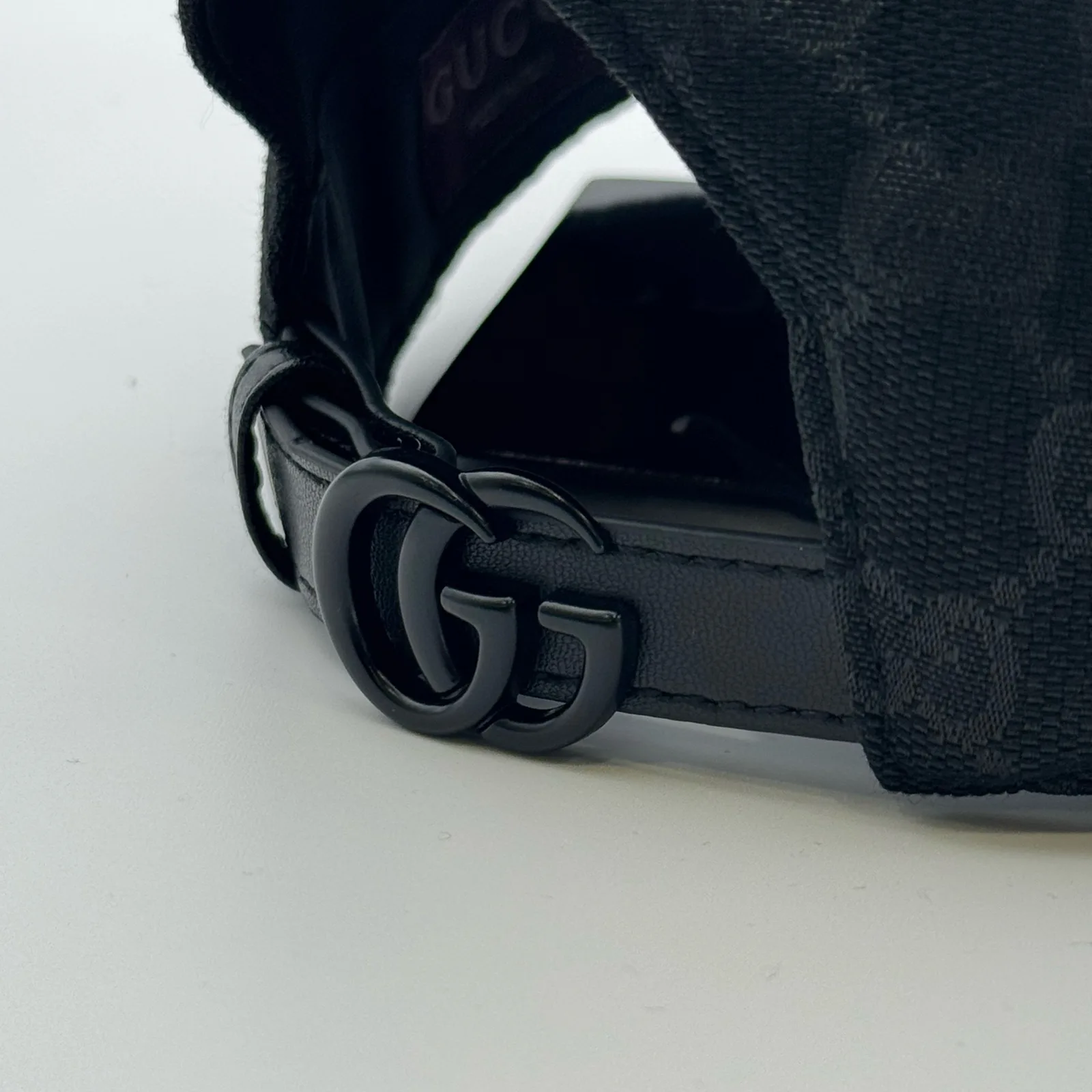 Black GG canvas cap, close-up of the GG-logo buckle hardware on the strap
