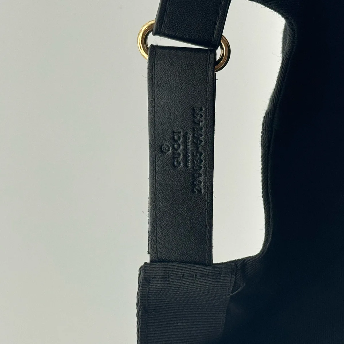 Black GG canvas cap, close-up of the leather strap with debossed Gucci wordmark