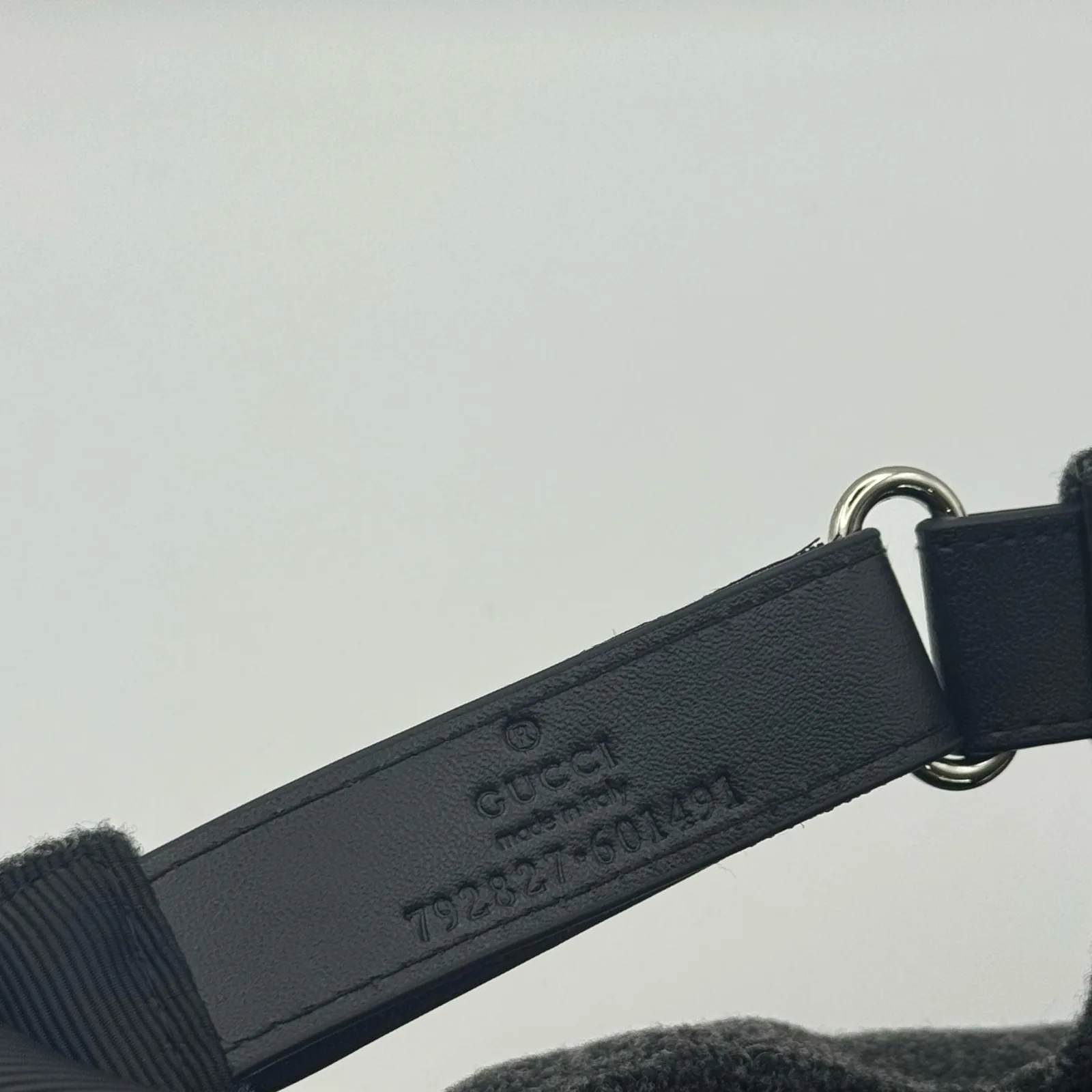Close-up of adjustable strap buckle and Gucci-stamped leather