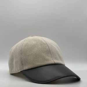 Hermès canvas cap, three-quarter view showing the black leather brim and tonal button.