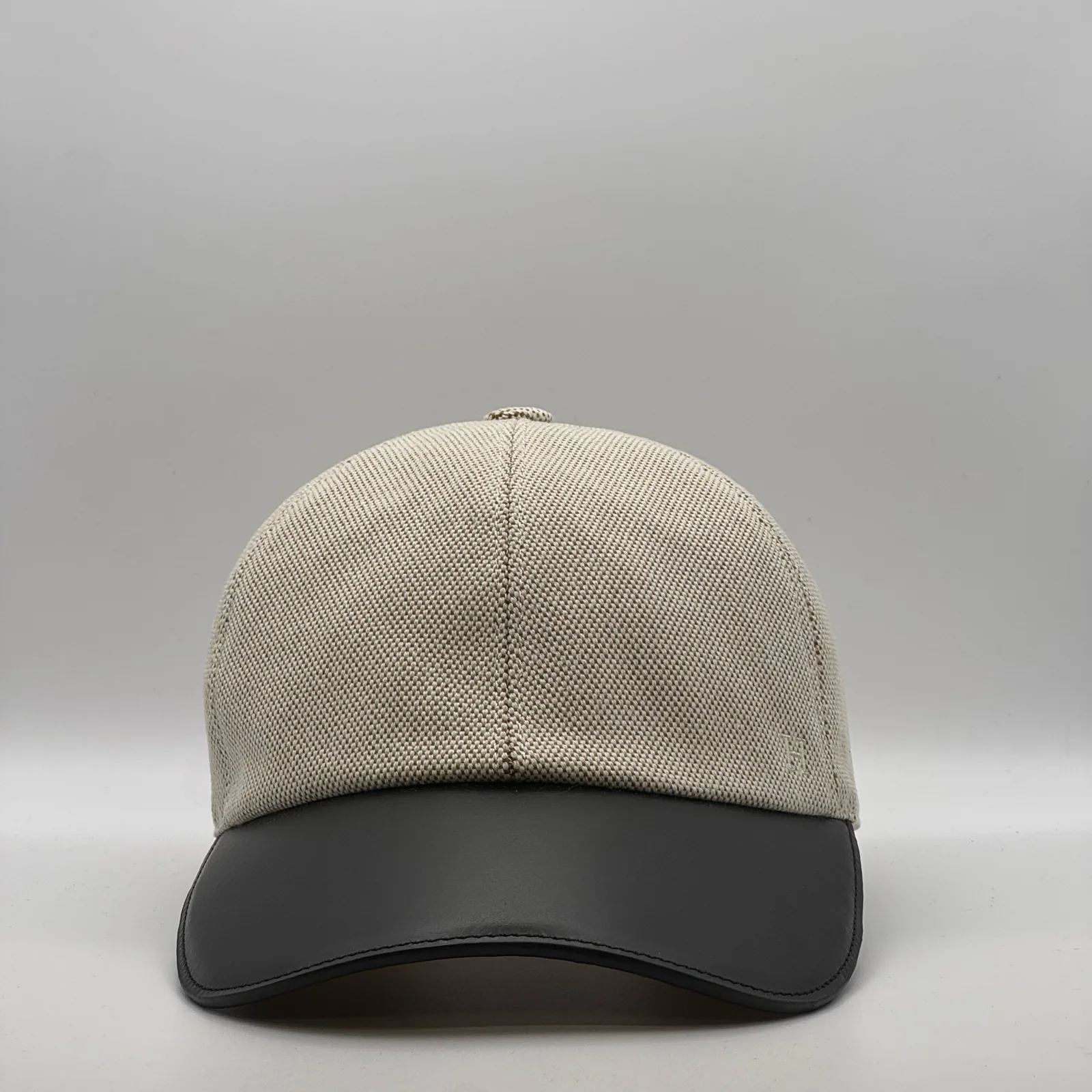 Hermès canvas cap, front view in oatmeal weave with a black leather brim.