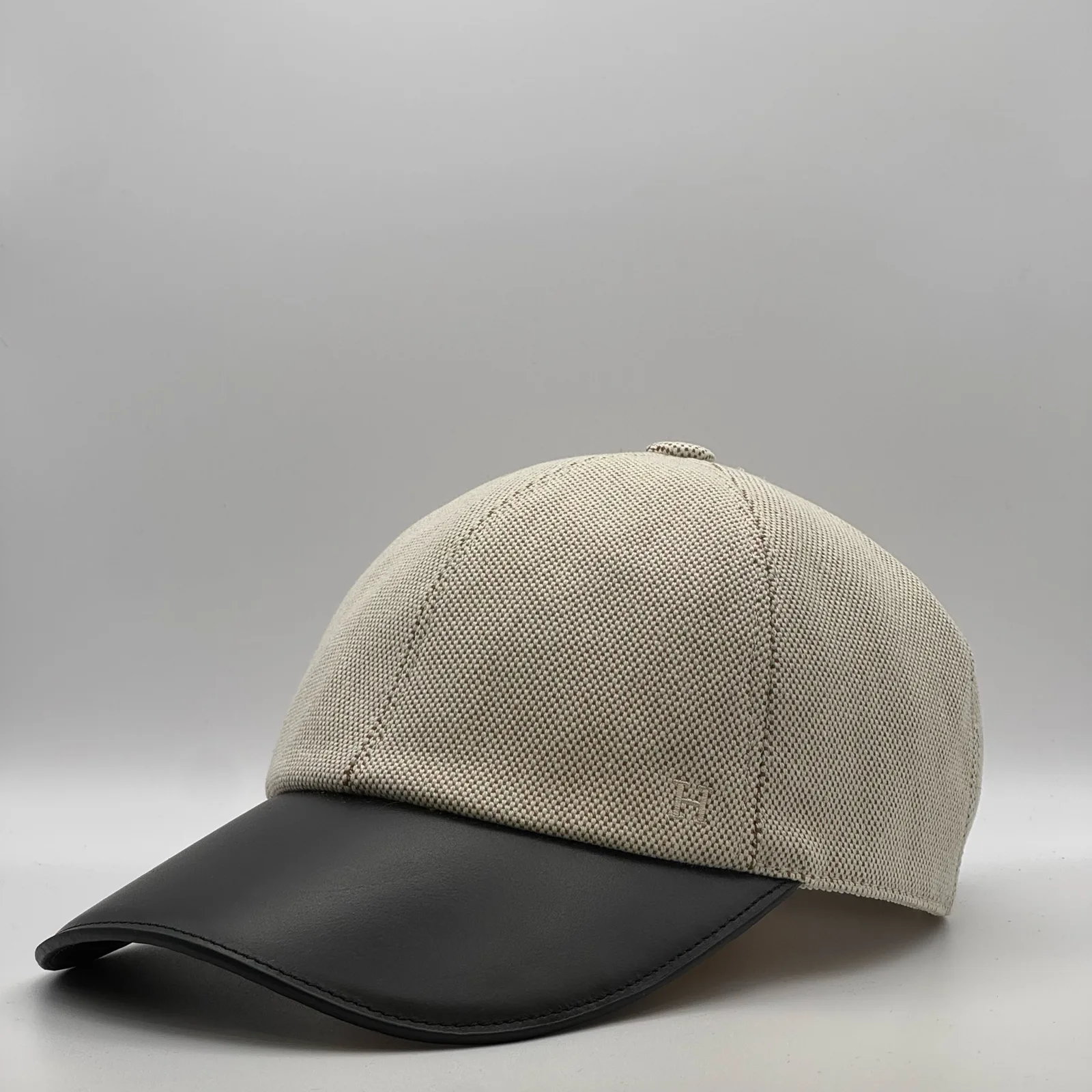 Hermès canvas cap, side profile in woven canvas with a black leather brim.