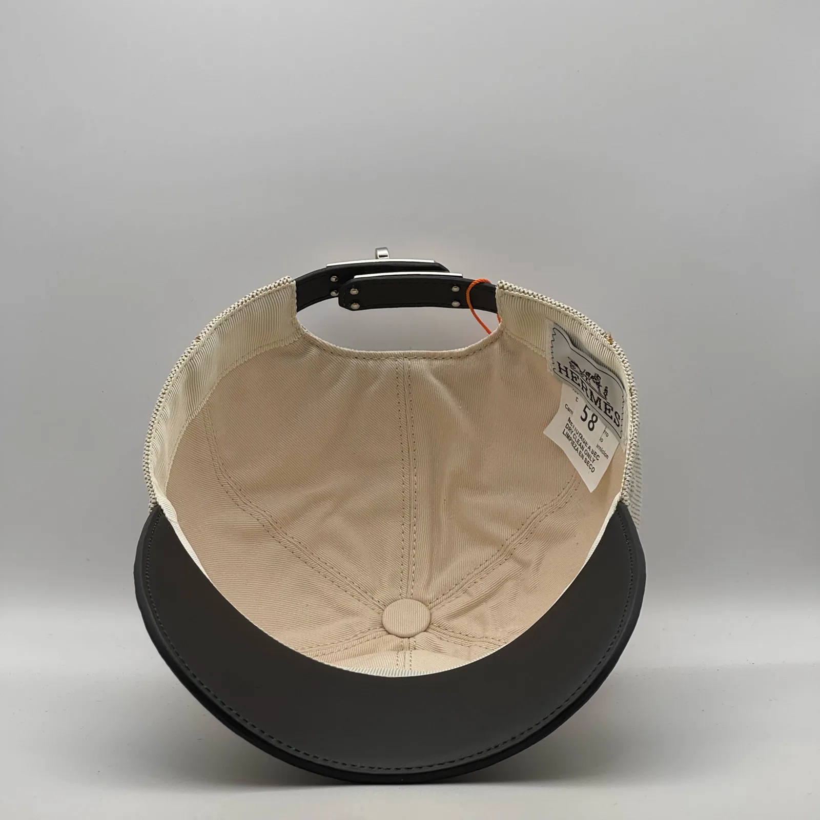 Hermès canvas cap, underside view showing the cream interior lining and black brim.