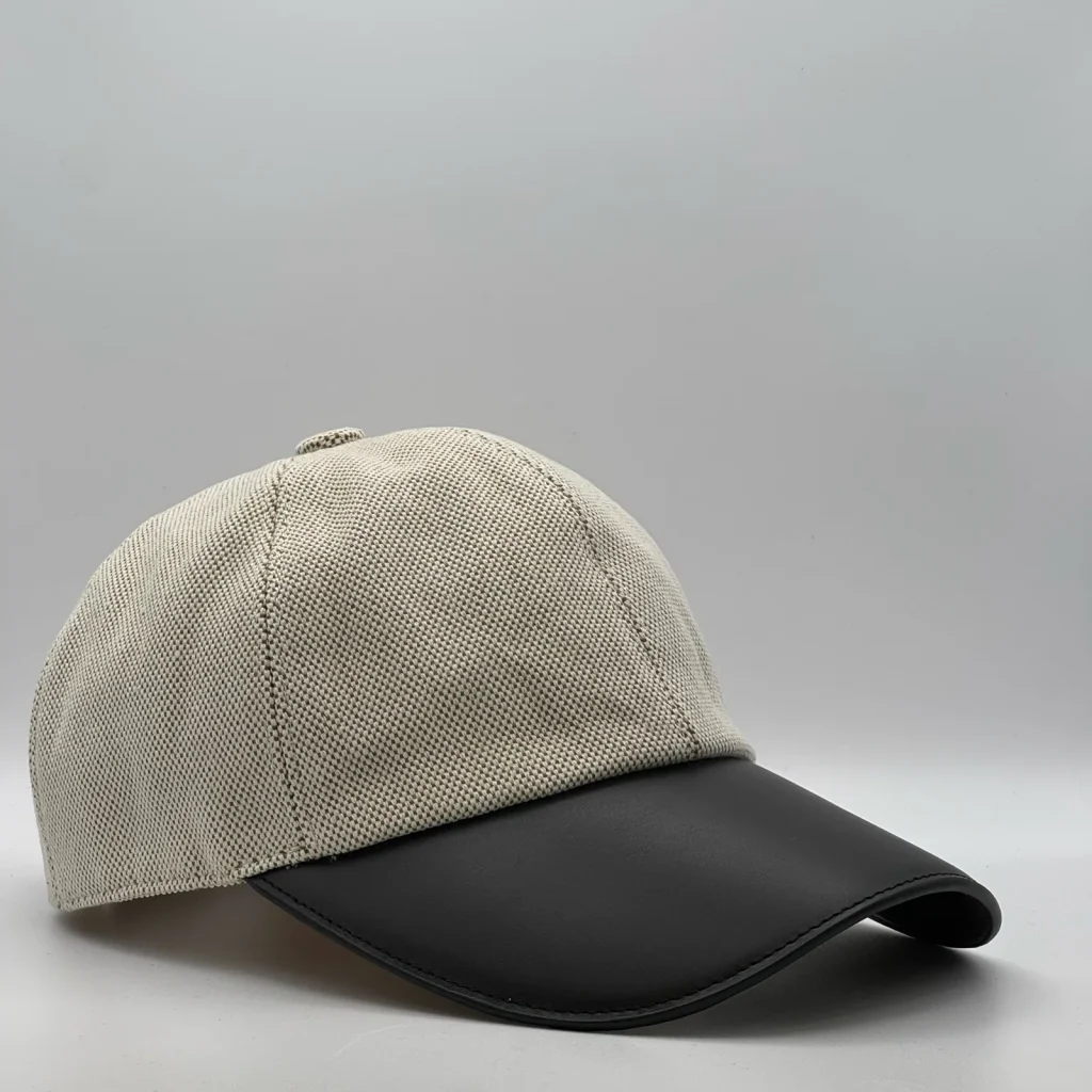 Hermès canvas cap, three-quarter view showing the black leather brim and tonal button.
