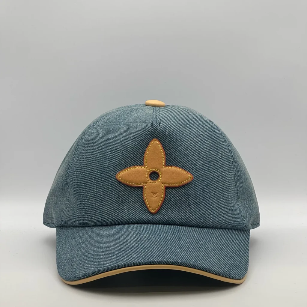 Blue denim Louis Vuitton Flower cap, front view showing the leather flower emblem.