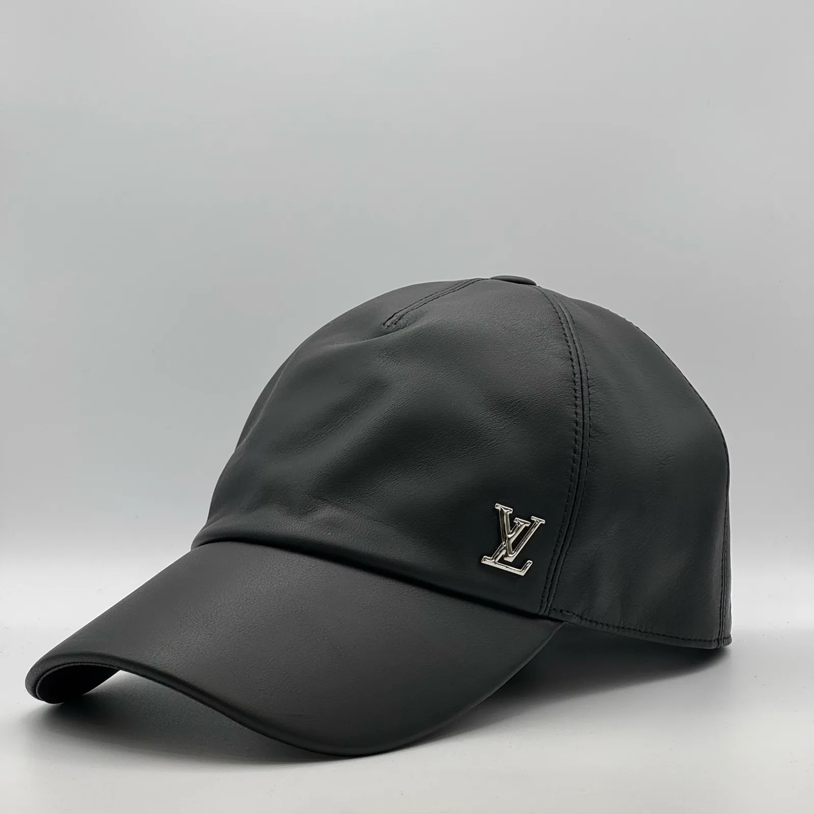 Black leather cap, angled view showing the LV metal logo.