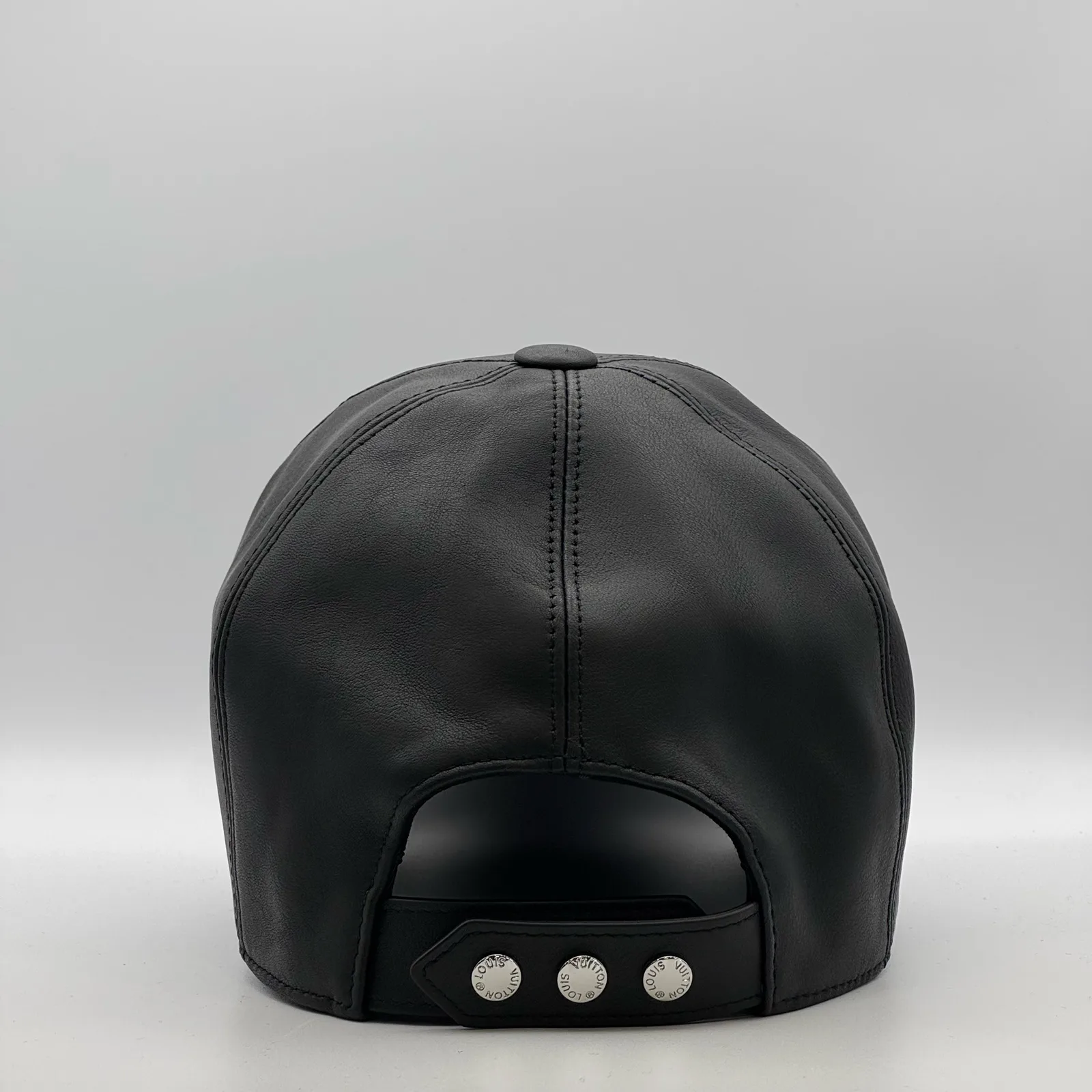 Black leather cap, back view showing the snap-stud closure.