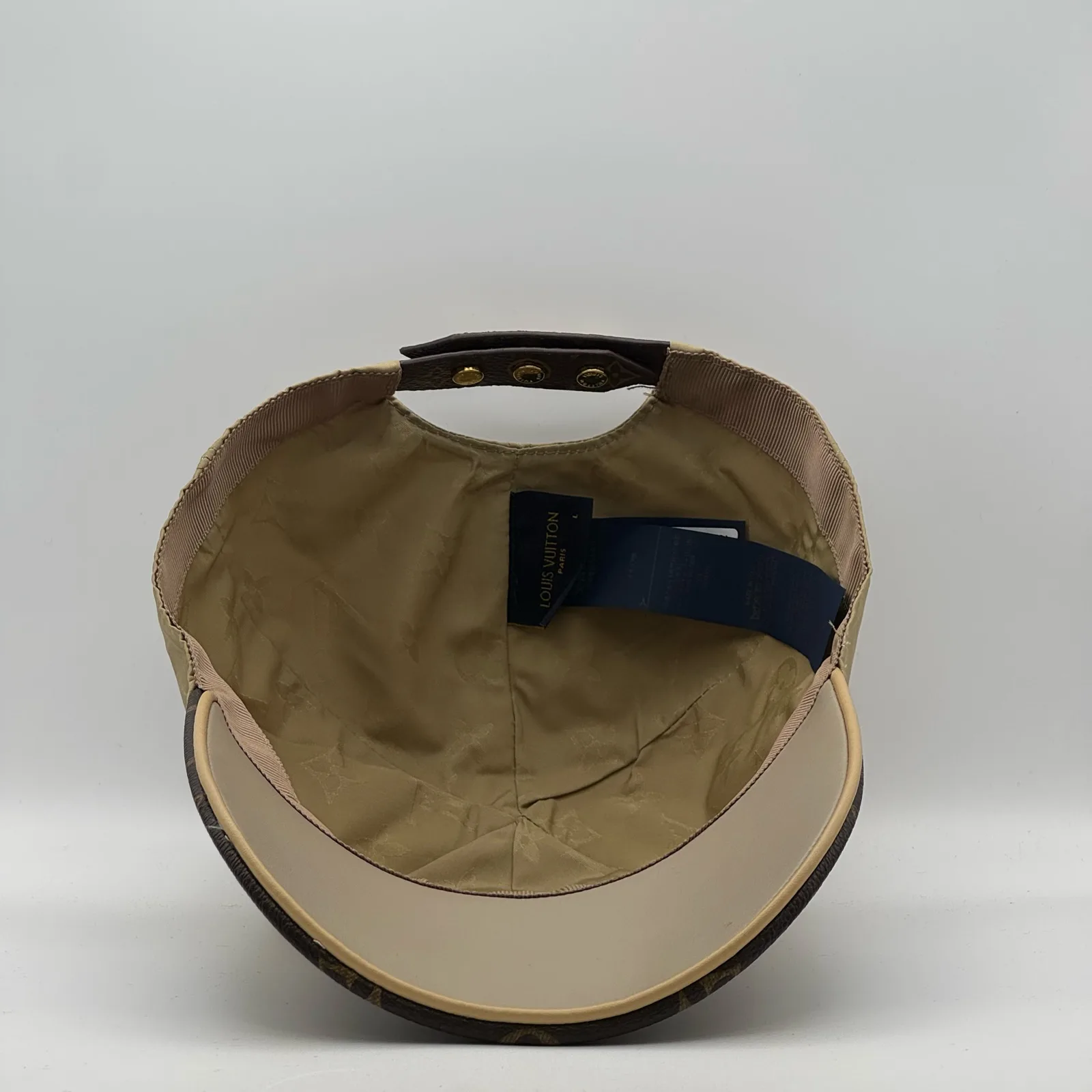 Inside view of the beige cap showing the strap and brand tape.