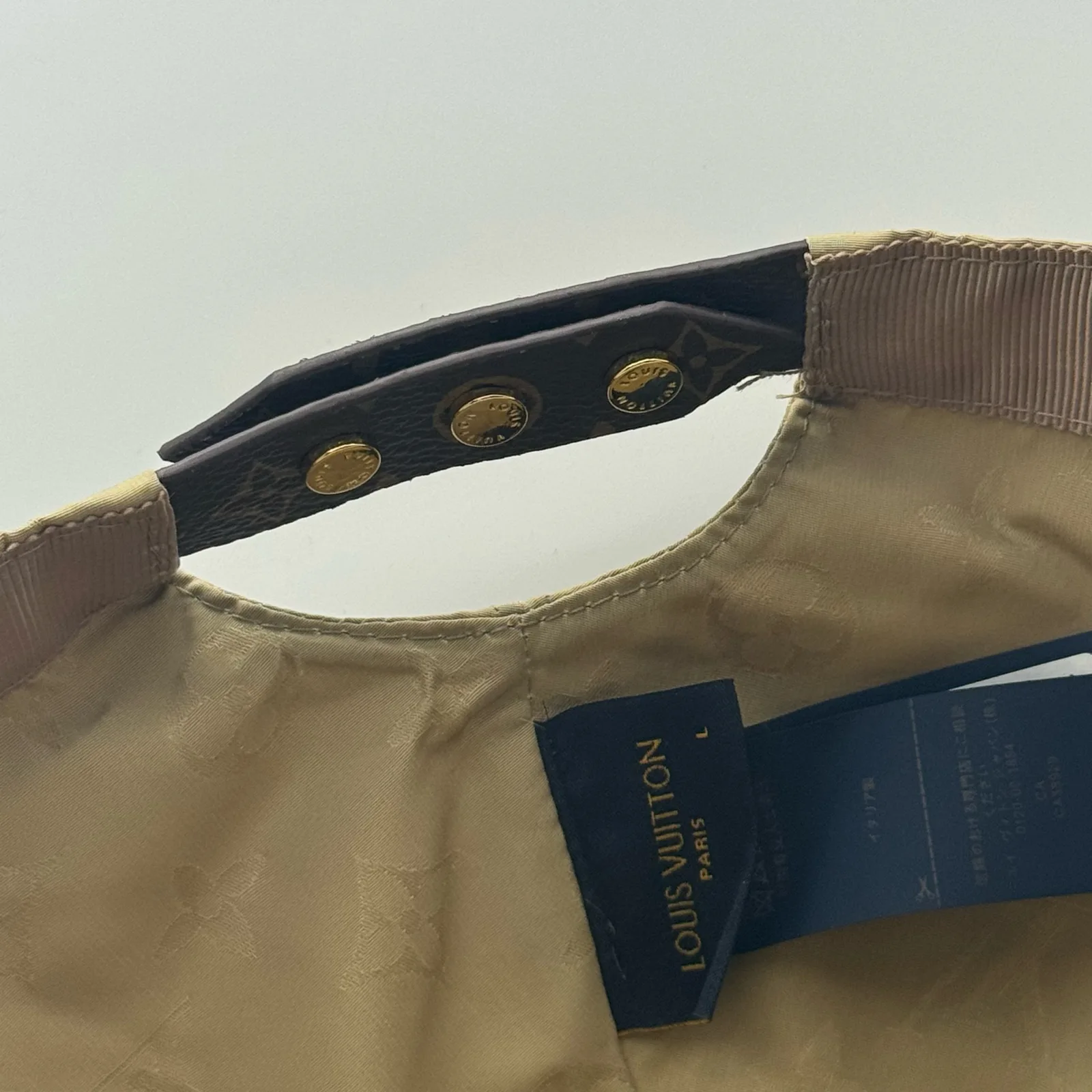 Close-up of the snap-stud closure and interior tag on the beige cap.