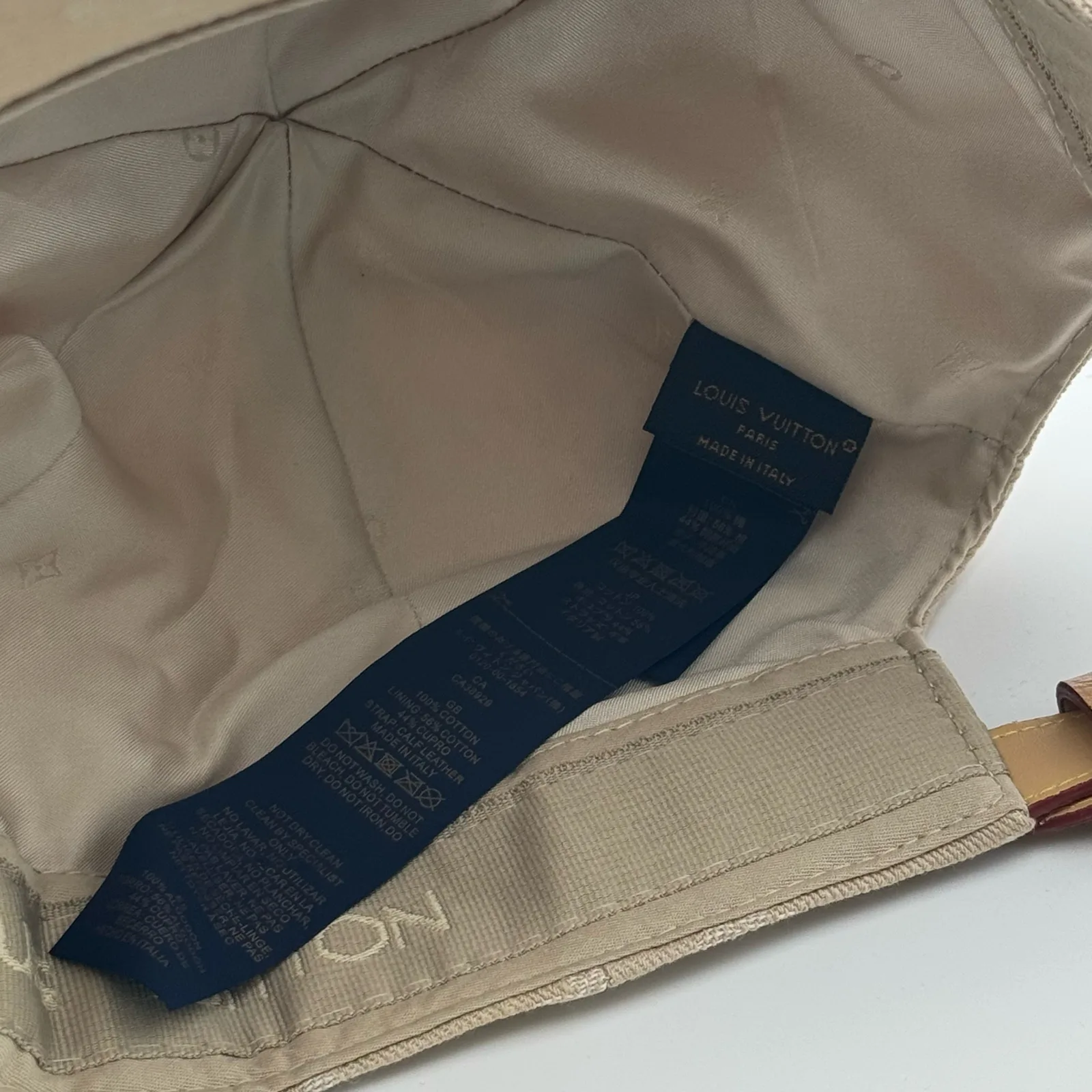 Inside view of the beige cap showing the lining and brand tag.