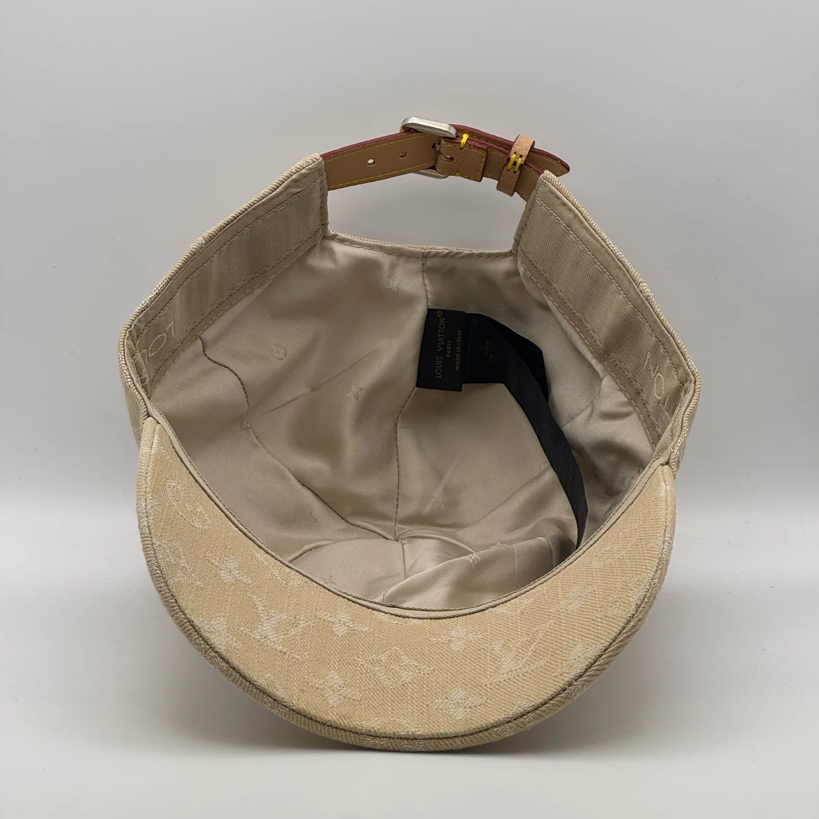 Inside view of the beige cap showing the strap and interior tag.
