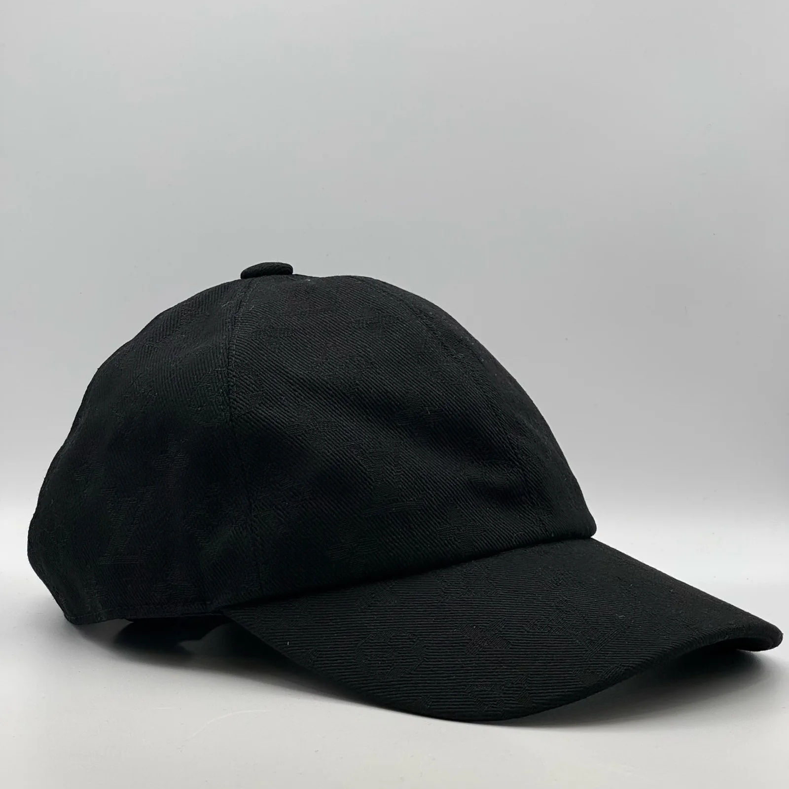 Black monogram jacquard cap, three-quarter side view.