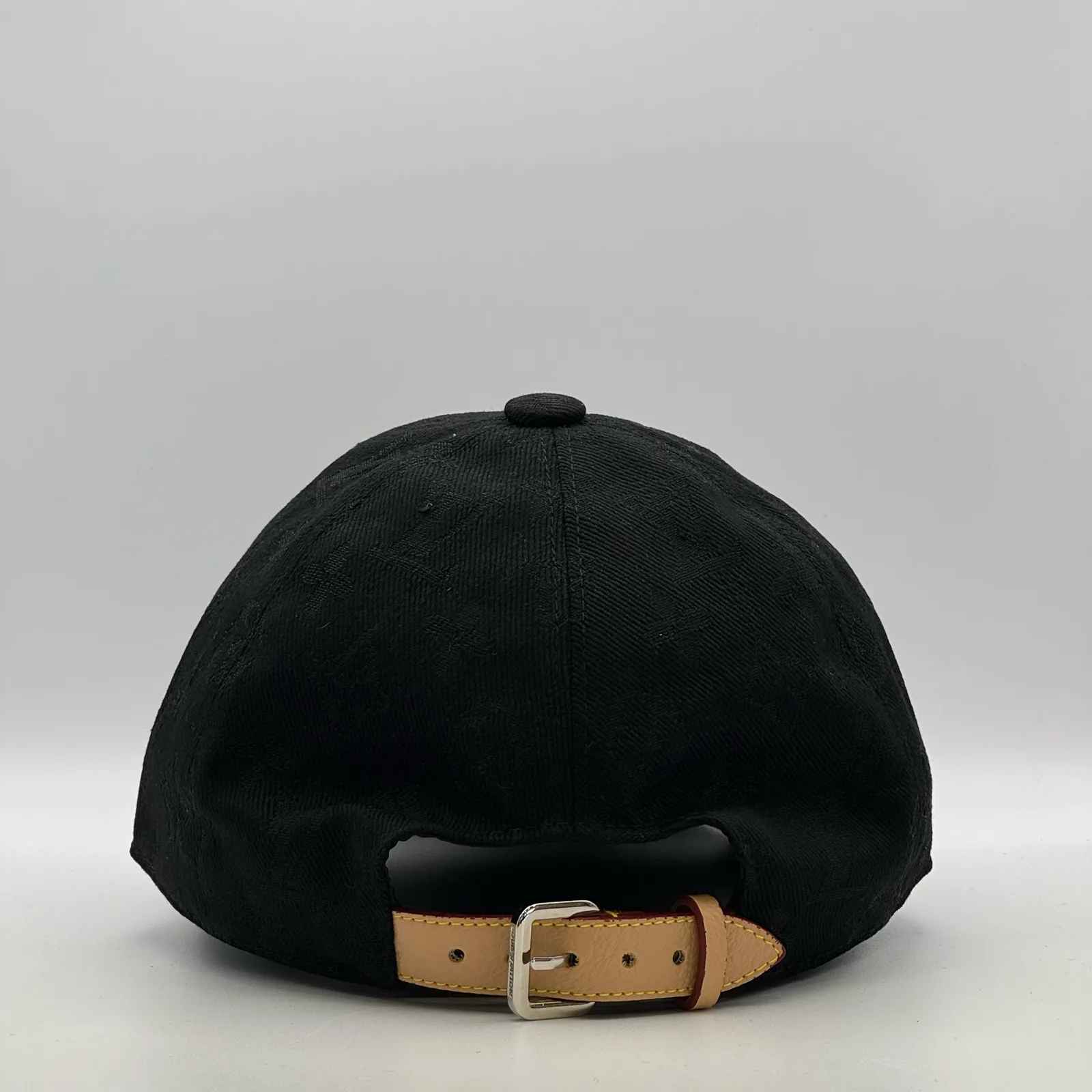 Black monogram jacquard cap, back view showing the tan leather strap.