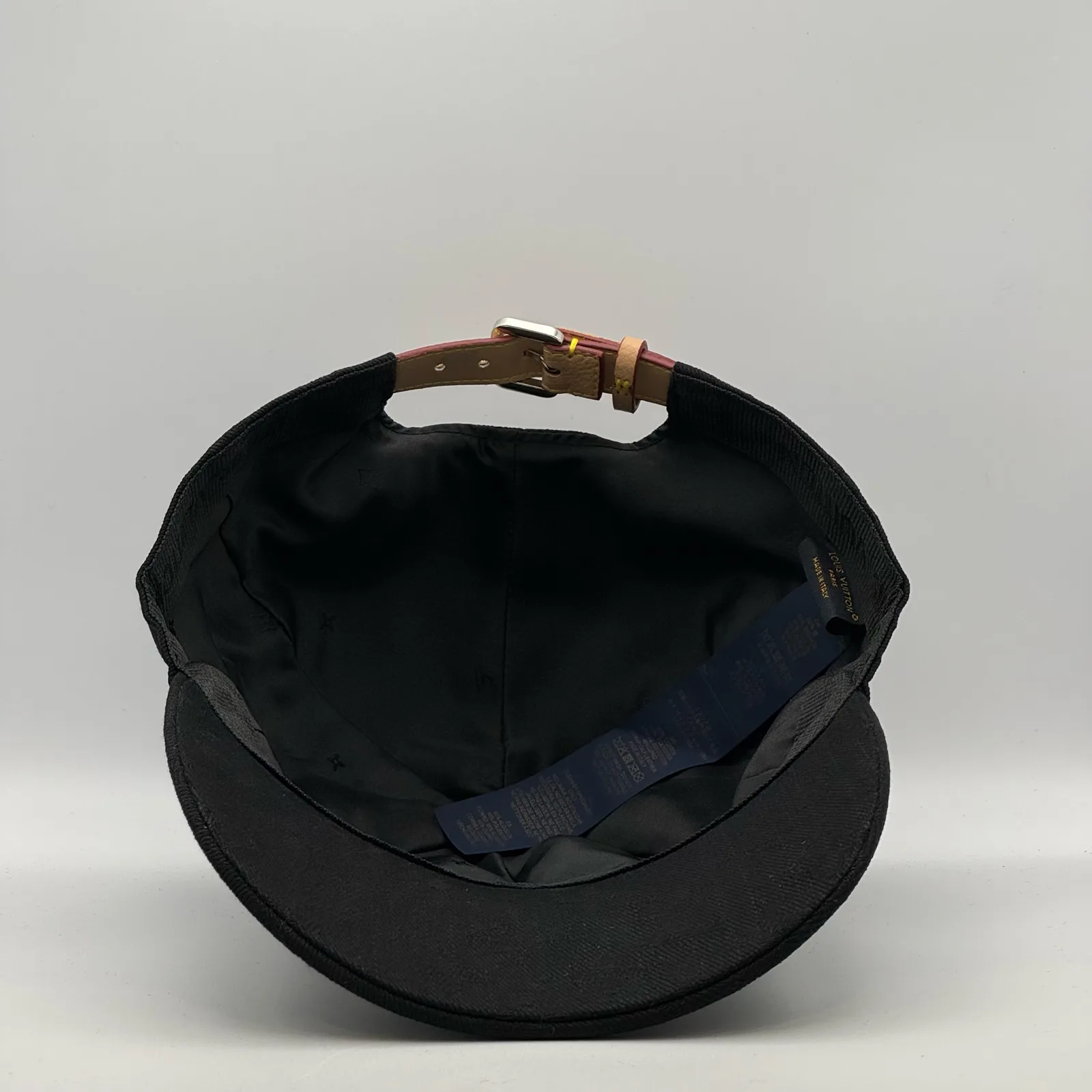 Underside view of the black jacquard cap showing the strap and lining.