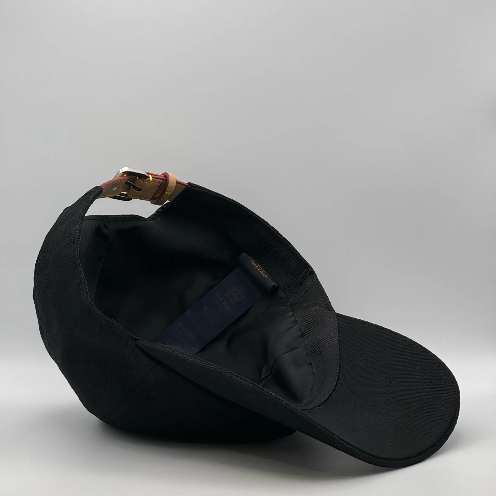 Angled inside view of the black jacquard cap and adjustable strap.