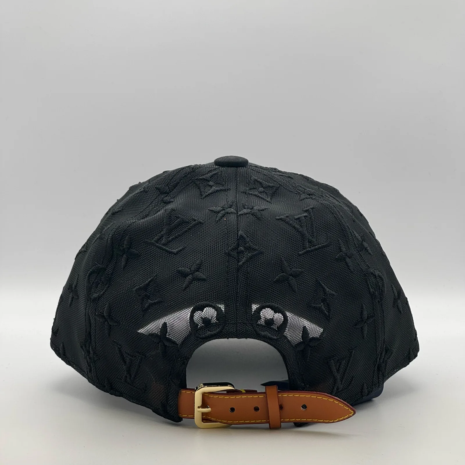 Black monogram mesh cap, back view showing the tan leather strap.