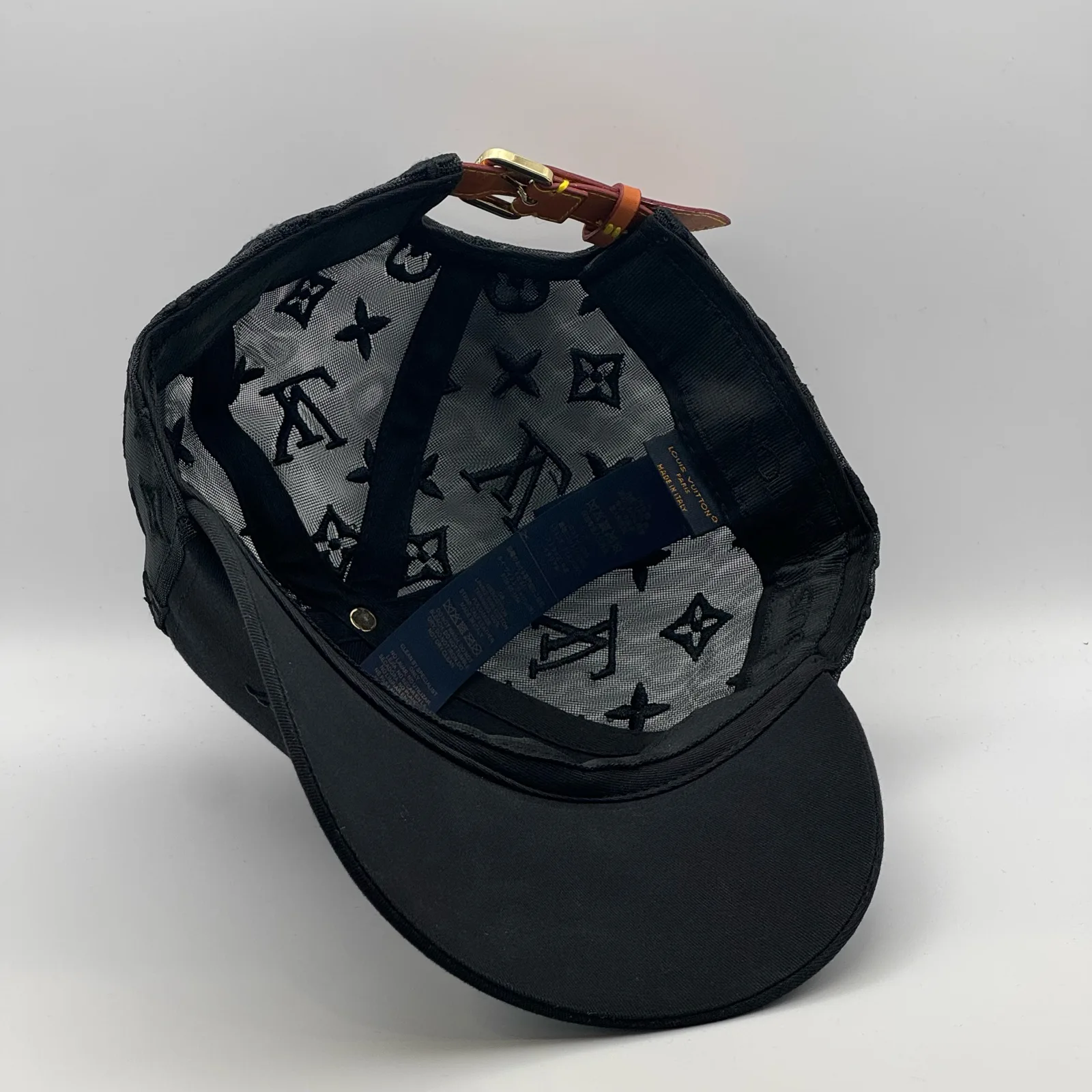 Inside view of the black monogram mesh cap showing the brand tag.