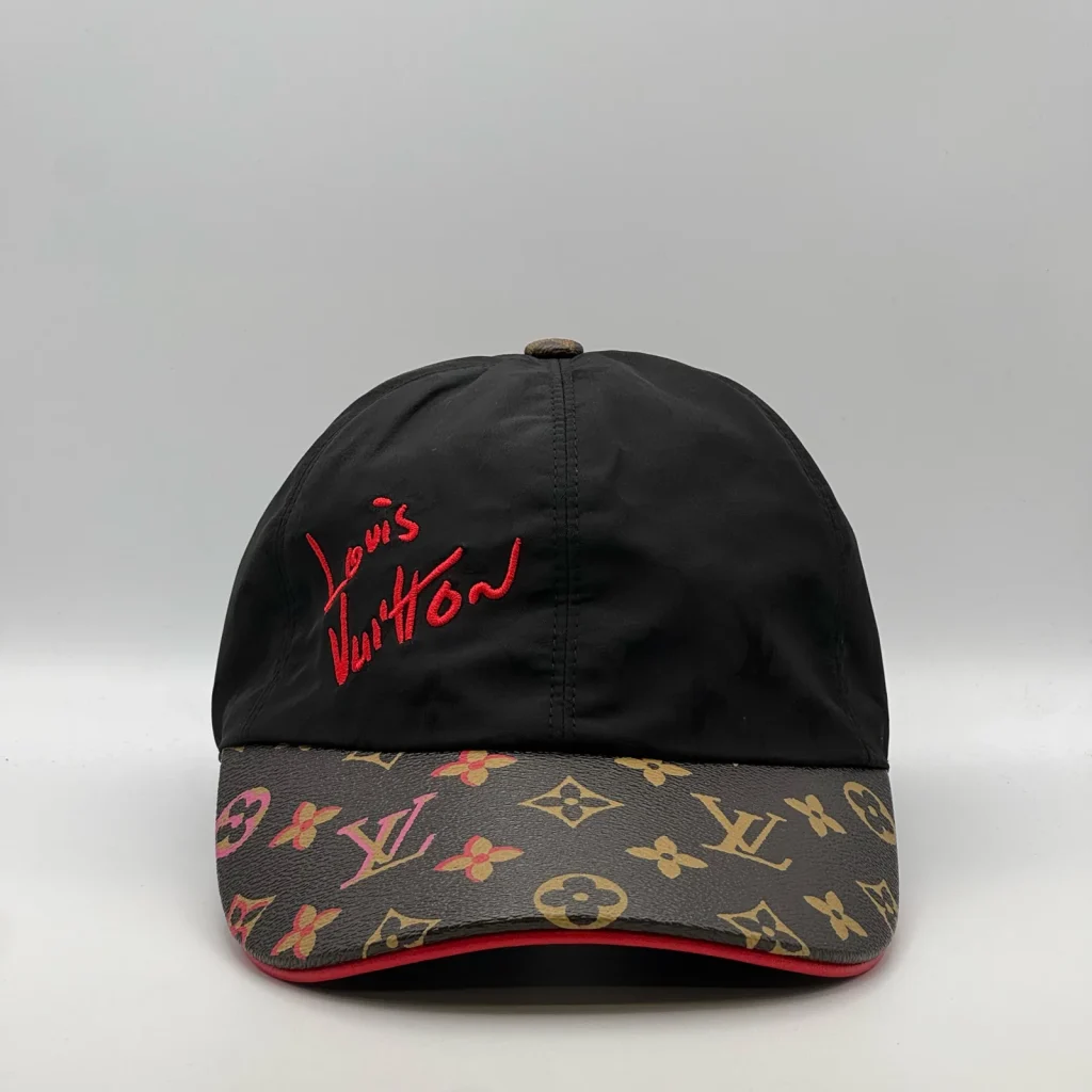 Black Louis Vuitton Signature cap, three-quarter view showing the red script logo and monogram brim.